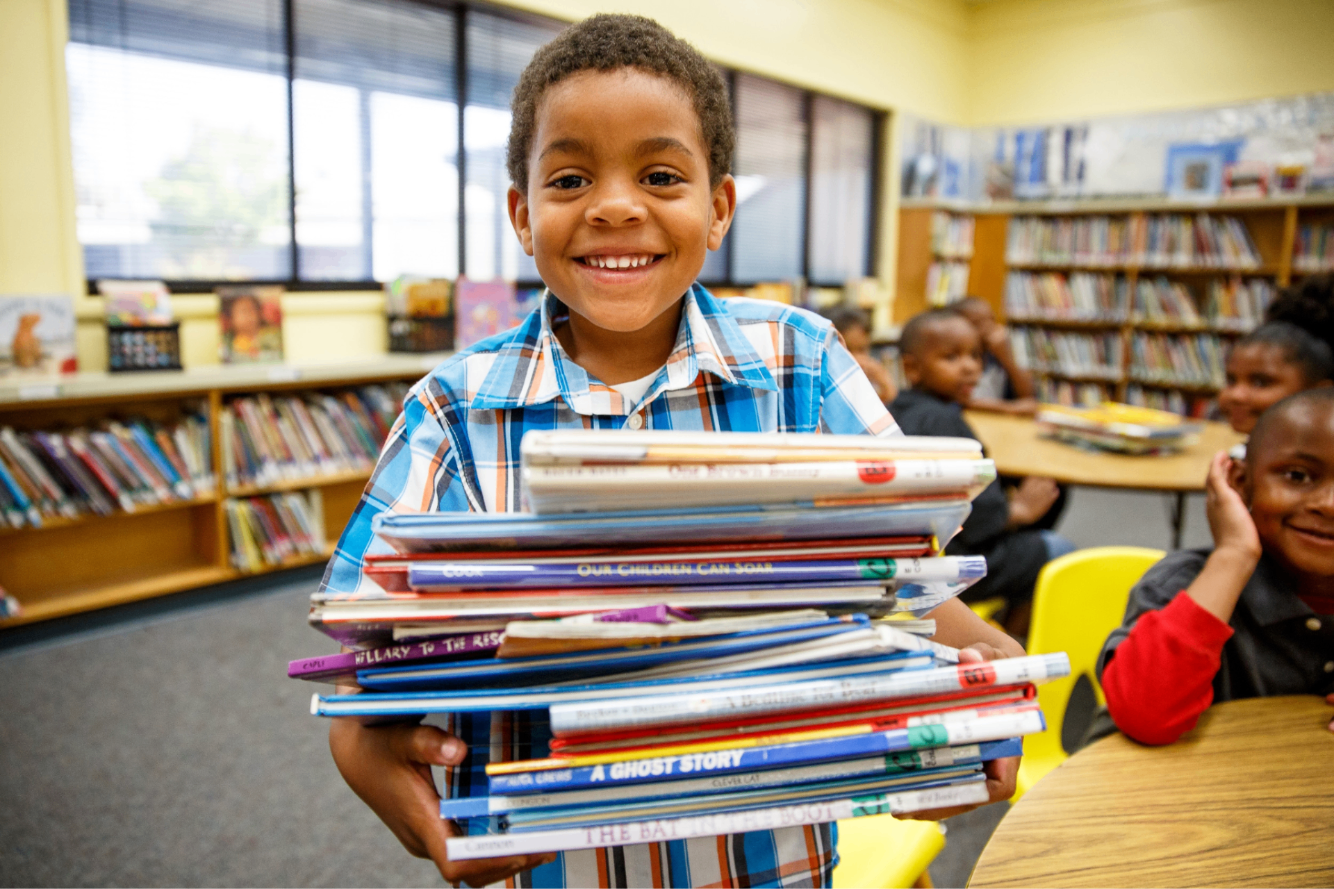 Smiling elementary student holding a stack of library books